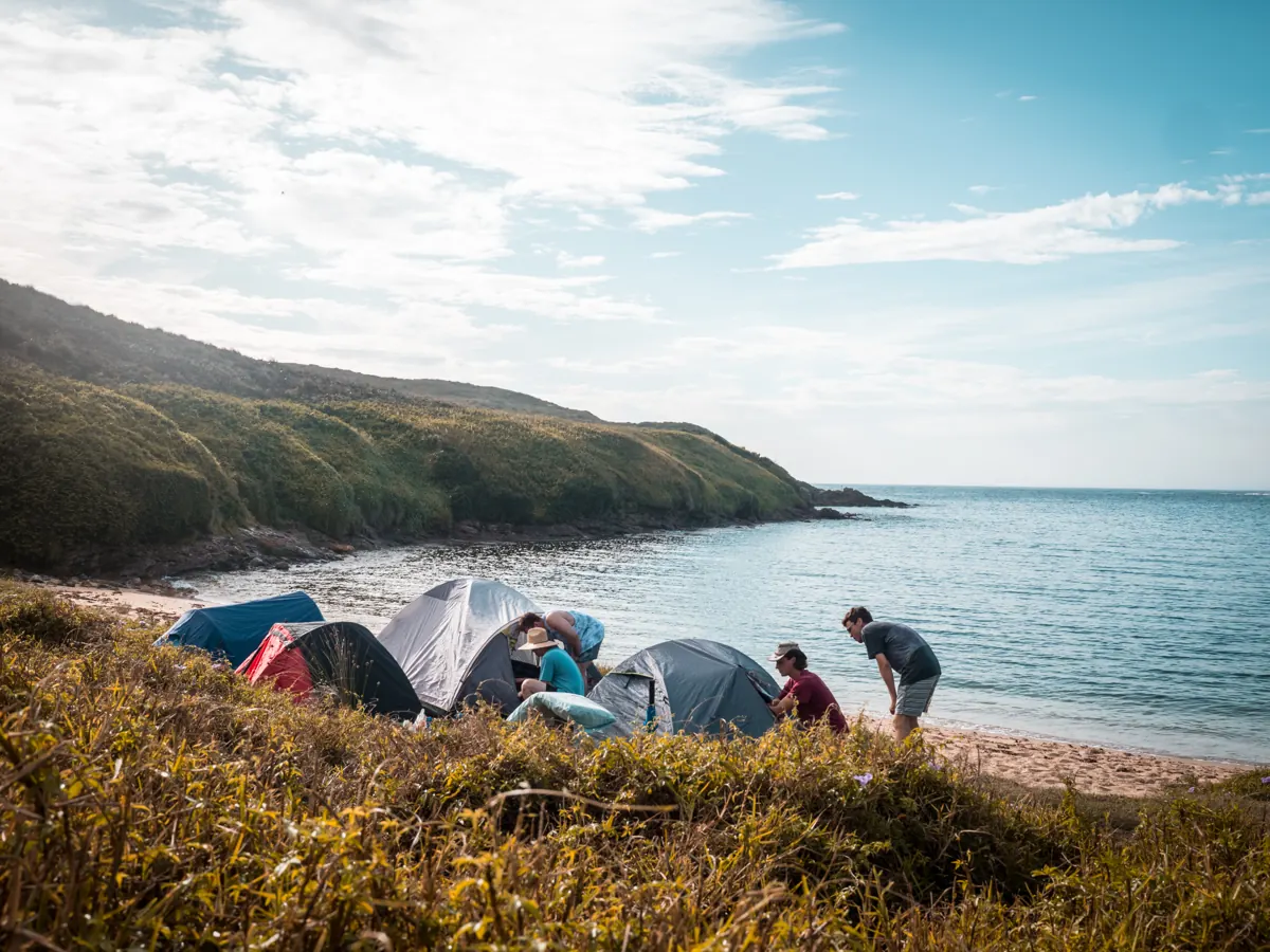 Setting up tents above the beach at an overnight coastal camp